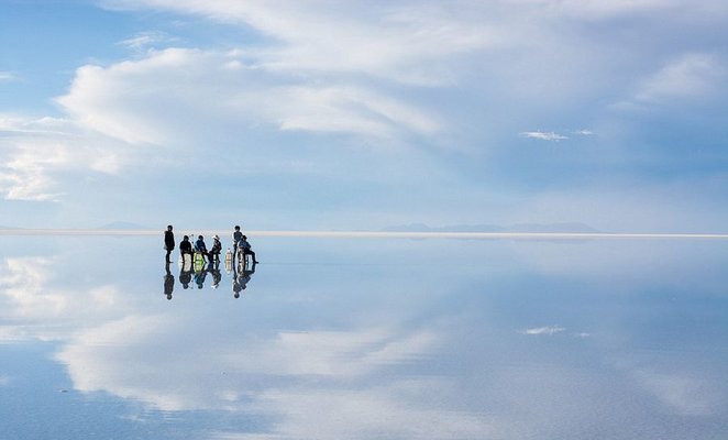 Os viajantes são reflectidos graças ao efeito de espelho durante a melhor altura para visitar o Salar de Uyuni