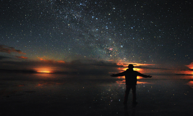 Viajante observa o céu estrelado durante a melhor época para visitar o Salar de Uyuni