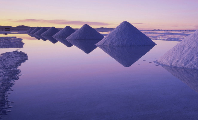 Os cones de sal reflectem-se na água durante a melhor altura para visitar o Salar de Uyuni.