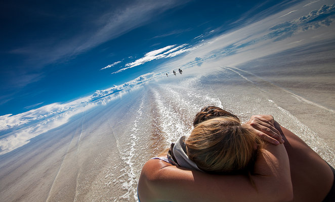 Dois viajantes sentados no salar inundado de Uyuni